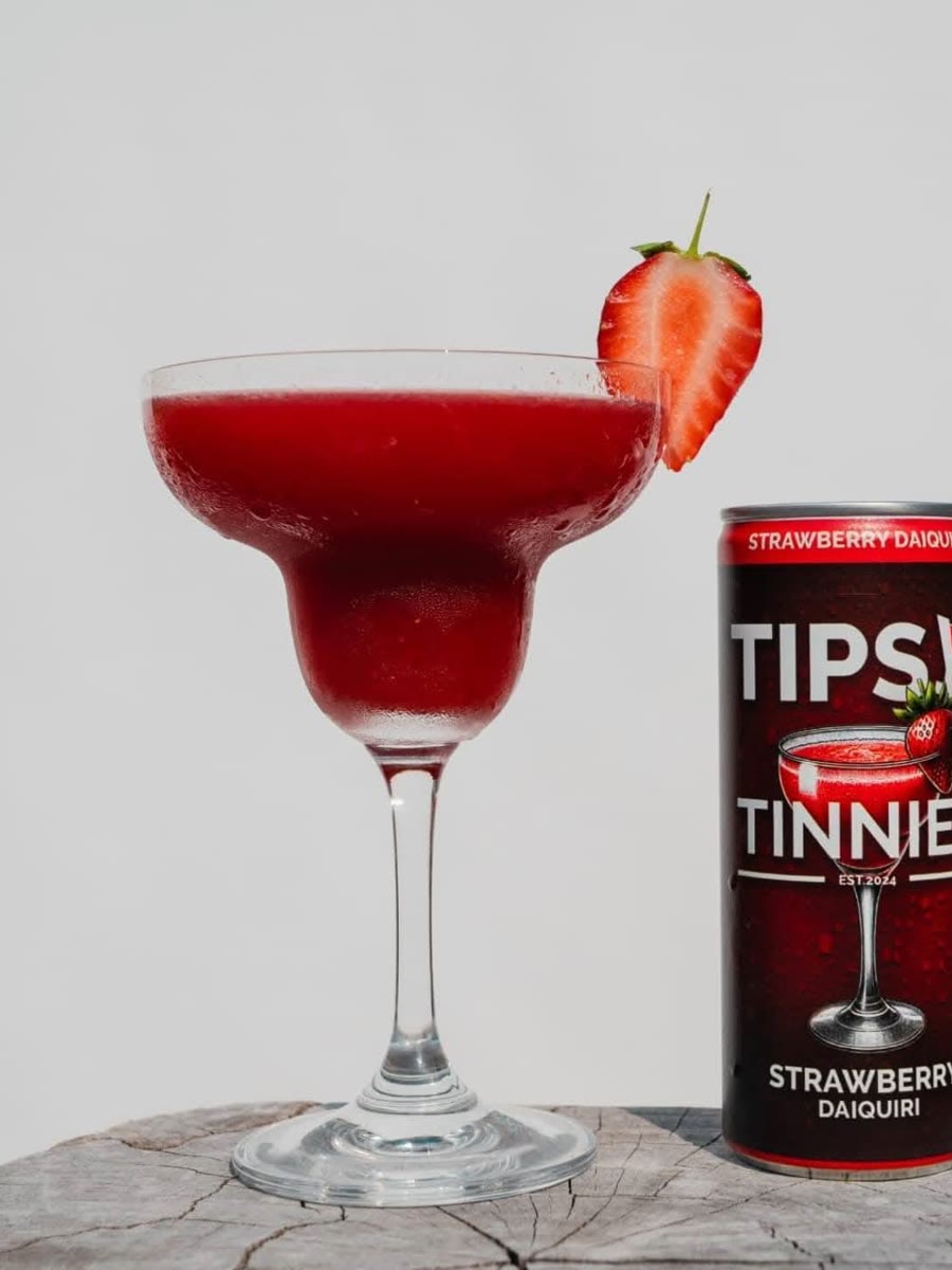 Strawberry Daiquiri in a margarita glass with a fresh strawberry, next to its tin