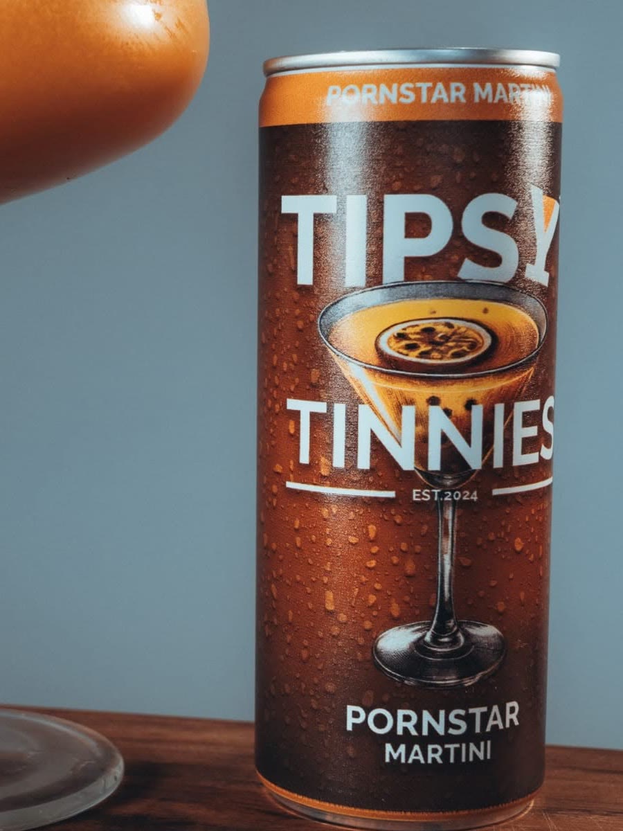 Pornstar Martini tin beside a full coupe on a wooden bar