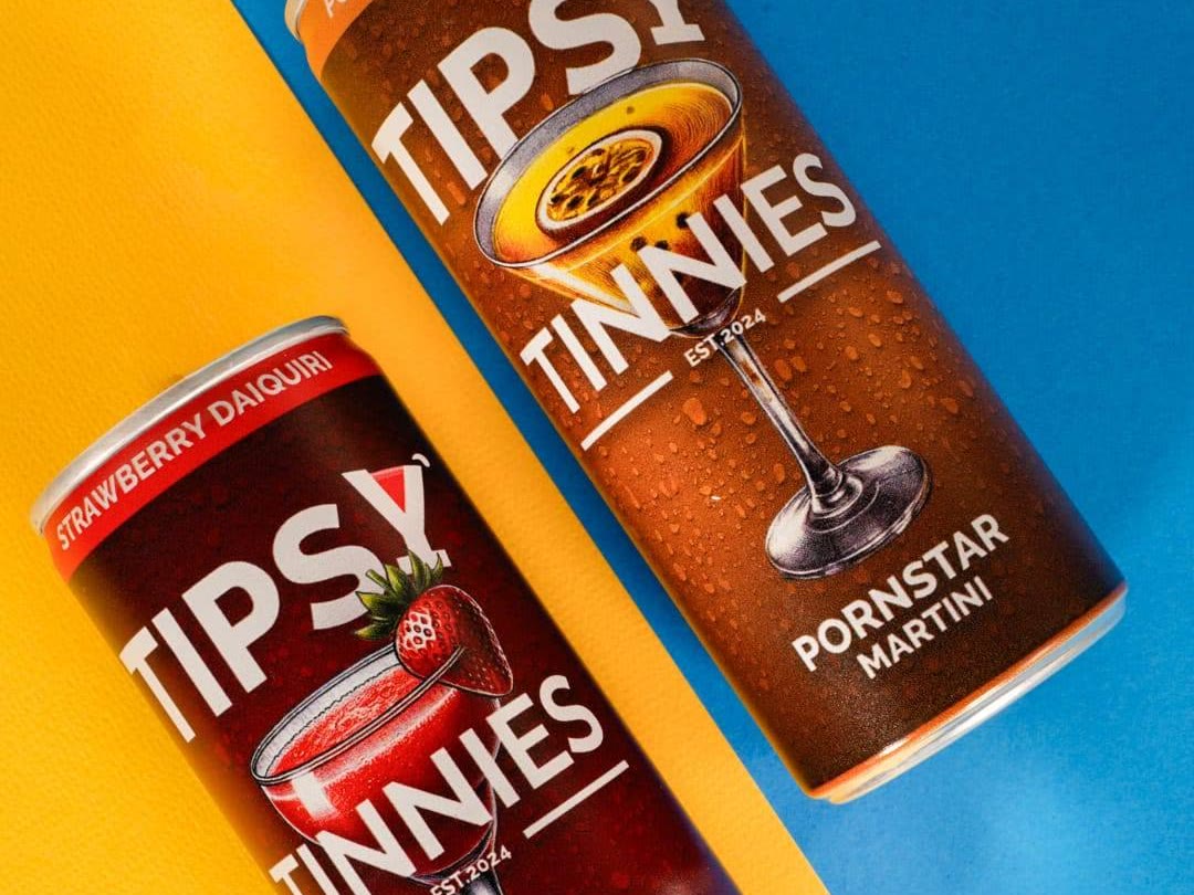 Strawberry Daiquiri and Pornstar Martini tins on a bright yellow and blue background